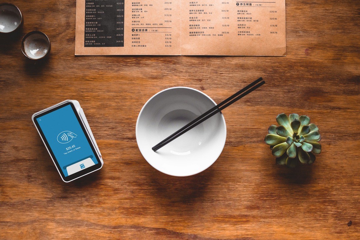 Ordering a restaurant meal online with Bestfood Restaurant table set with a printed menu, ceramic bowls and chopsticks, and a phone tapping to pay
