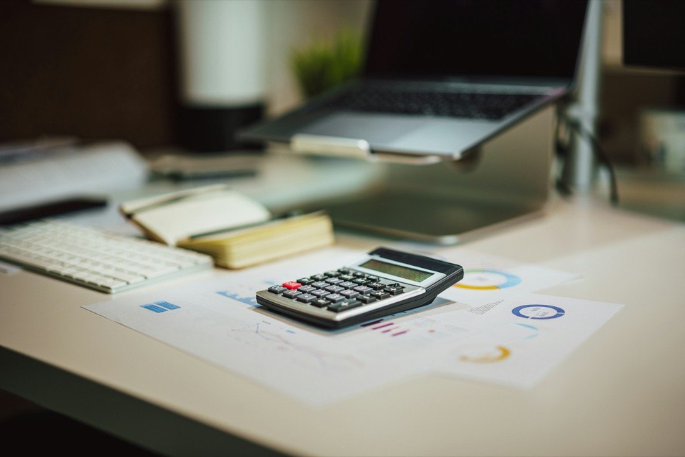 Calculator, financial statements and a laptop on an office desk