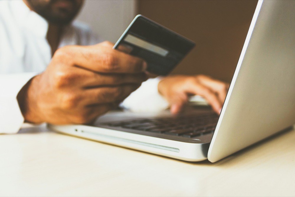 Shopper holding a credit card while paying for an online order on a laptop
