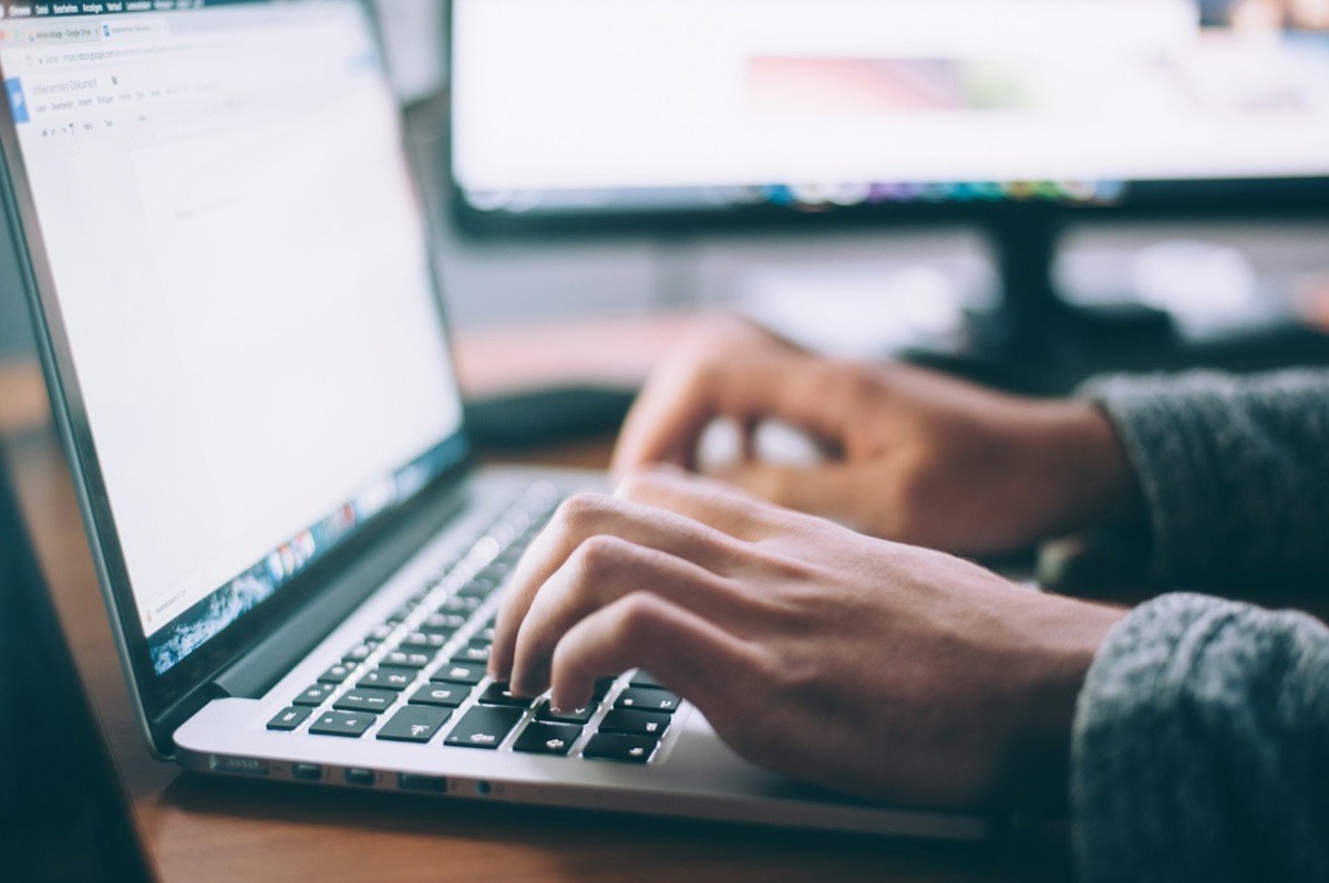 Designer building website pages on a laptop connected to an external monitor
