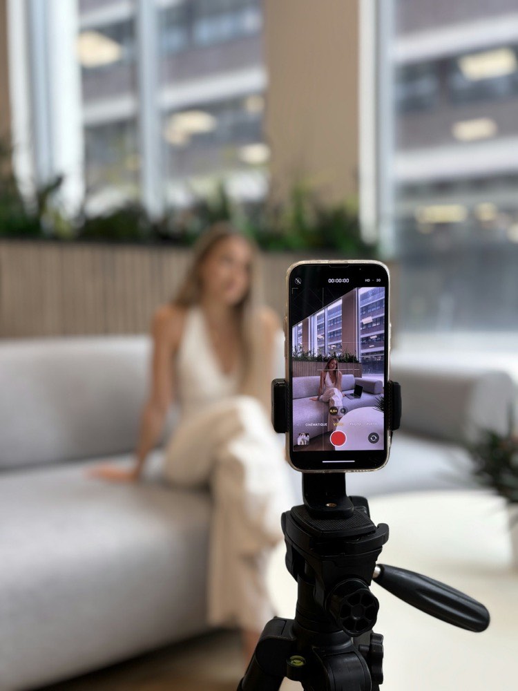 Phone mounted on a tripod recording content, with the screen showing a recording in progress