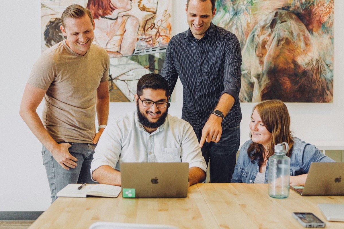 Four colleagues gathered around a laptop discussing a project